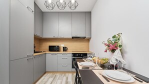 Eine moderne Küche mit grauen Schränken, einer Holzarbeitsplatte und einem Essbereich mit Tisch, Stühlen und einem Blumenstrauß.