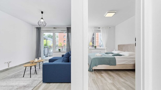 Eine moderne Wohnung mit Sofa, kleinem Tisch, Bett und Blick auf die Stadt.