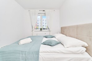 A neatly made bed with a white headboard, a blue blanket, and a white towel.