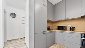 Eine moderne Küche mit grauen Schränken, einer Mikrowelle, einer Kaffeemaschine und einer Uhr an der Wand.