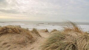 Una playa con dunas de arena y cielo nublado.