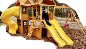 Une cabane en bois pour enfants, avec un toboggan et une balançoire.