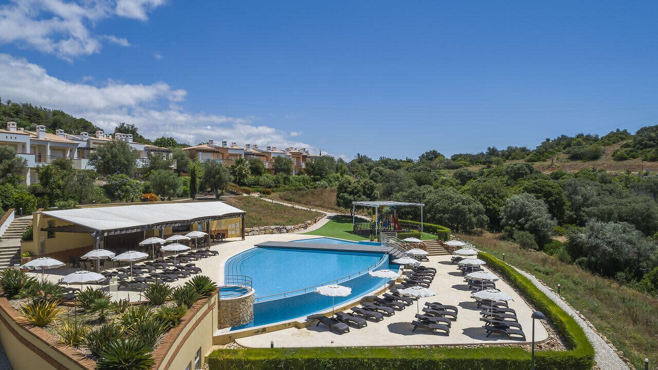 A resort with a swimming pool, sun loungers, and outdoor seating.