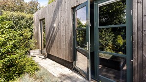 A modern wooden building with large glass doors and windows, surrounded by lush greenery. - Zandvoort Lodge 2 - Amazing couples getaway! (Zandvoort)