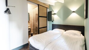 A modern hotel room with a large bed, a wardrobe, a mirror, and a wall-mounted TV. - Zandvoort Lodge 2 - Amazing couples getaway! (Zandvoort)