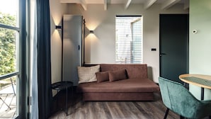 A modern living room with a brown sofa, a small table, and a green chair. - Zandvoort Lodge 2 - Amazing couples getaway! (Zandvoort)