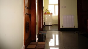 A hallway with a wooden door, a radiator, and a window with natural light. - Second Home (London)