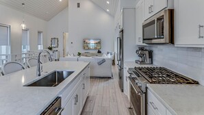 Una cocina moderna con una isla grande, electrodomésticos de acero inoxidable y vistas al área de estar.