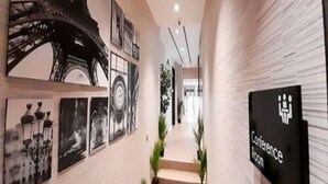 Un pasillo con un cartel que indica una sala de conferencias, una escalera y obras de arte en la pared, incluyendo una representación de la Torre Eiffel.