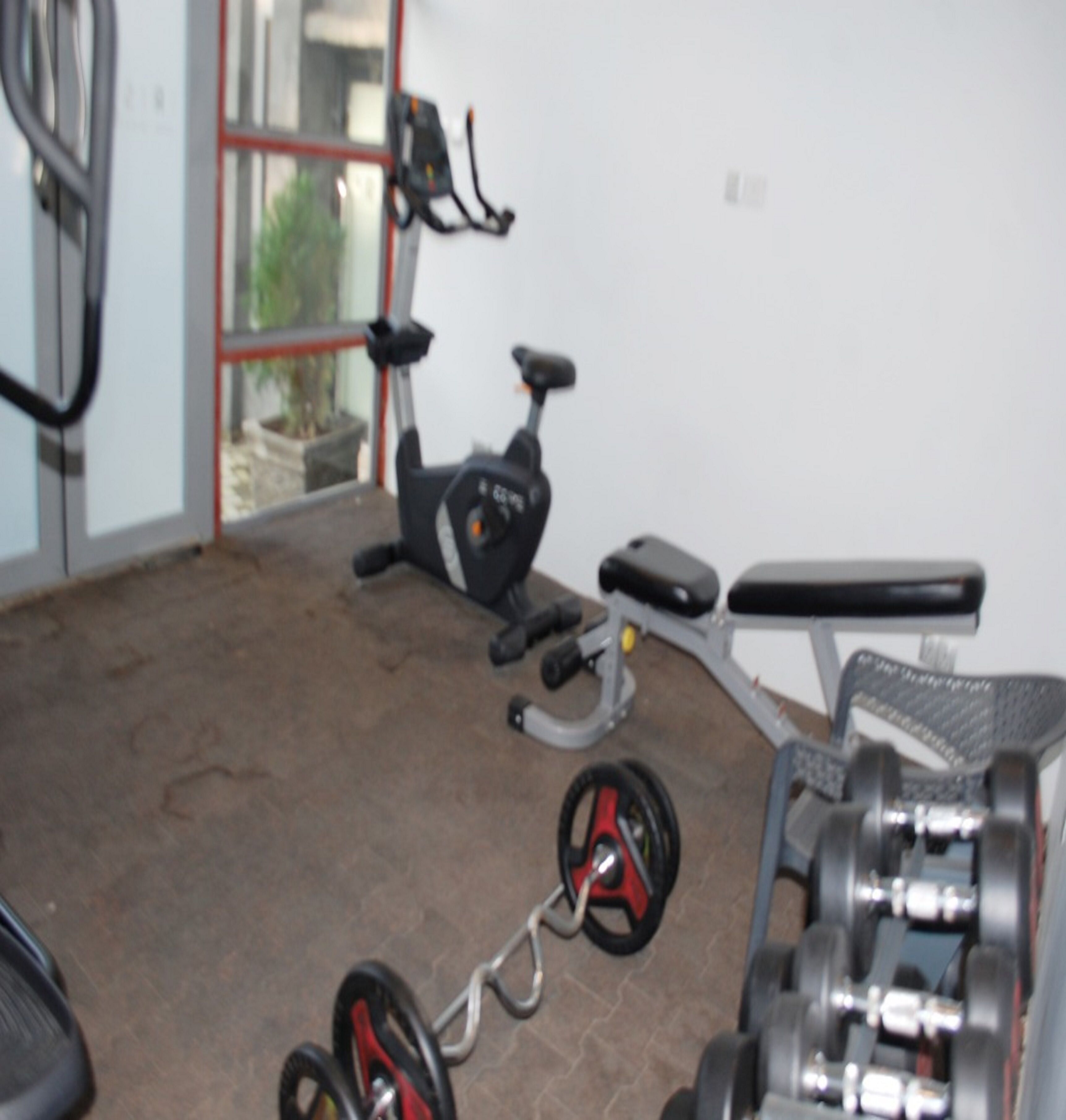 A gym with exercise equipment including a stationary bike, a treadmill, and a bench.