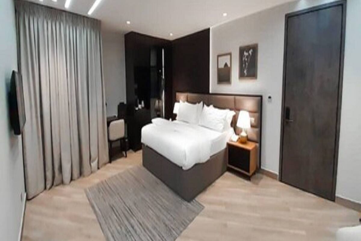 A modern bedroom with a large bed, bedside tables, a desk, and a wardrobe.