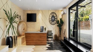 Una recepción moderna con un mostrador de madera, un reloj grande en la pared y un televisor de pantalla plana.