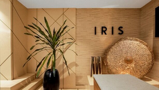 Un interior moderno con una pared de madera, una planta grande en maceta y la palabra 'IRIS' escrita.