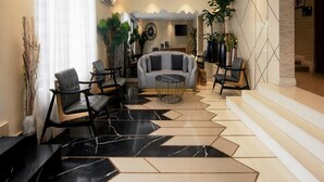 Una sala de estar moderna con un sofá, sillas y una mesa de centro. Una escalera conduce a otro nivel.