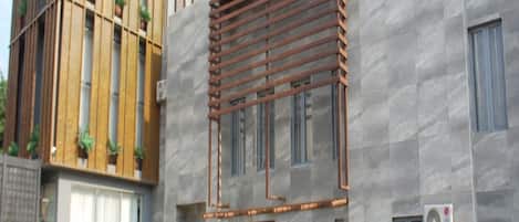 Un edificio moderno con una combinación de fachadas de madera y piedra, ventanas amplias y plantas en macetas al frente.