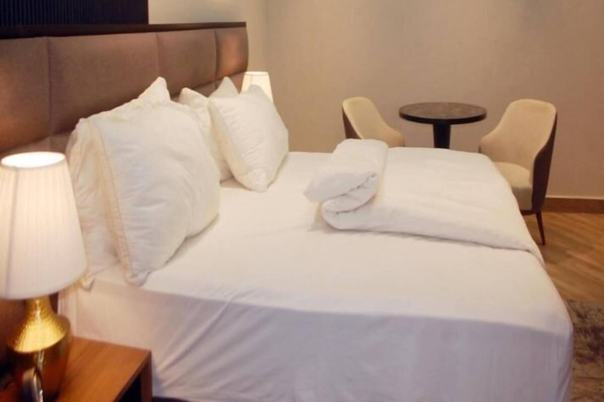 A hotel room with a bed, a bedside lamp, a round table, and two chairs.