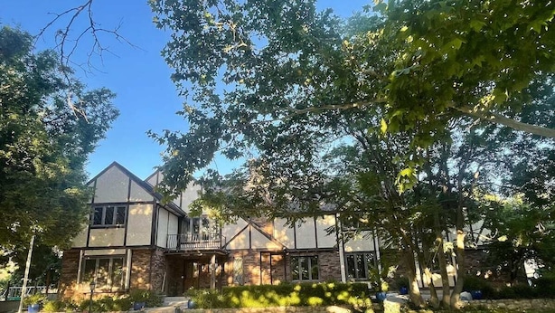 A two-story house with a balcony, a front porch, and a well-maintained lawn.