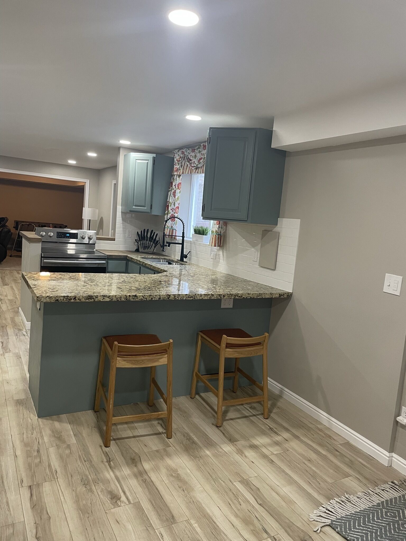 A kitchen with a granite countertop, two wooden bar stools, and a built-in oven.