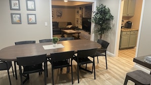 A dining area with a large oval table, black chairs, and a potted plant.