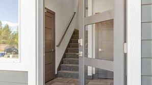 Un escalier menant à un deuxième étage, une porte et une vue sur l’extérieur.