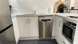 A compact kitchen with a dishwasher, oven, and a sink.