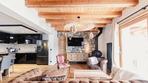 Ein modernes Wohnzimmer mit Kamin aus Stein, Holzbalkendecke und einer großen Ledersofa.