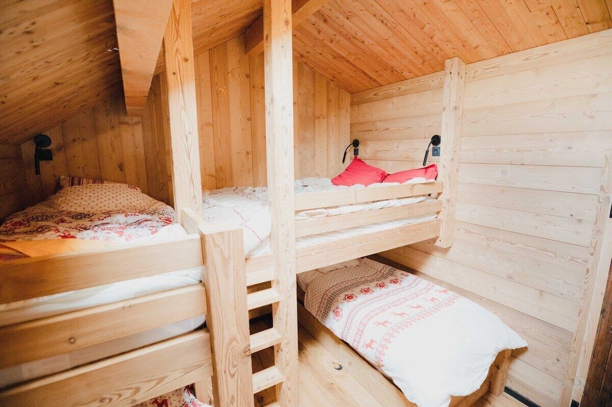 A wooden cabin with bunk beds, a ladder, and a small bench.