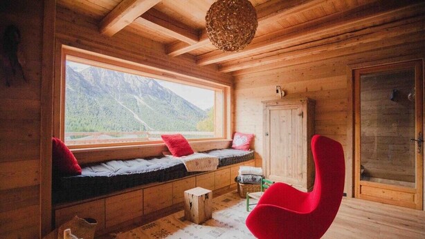 Ein Holzhütten-Interieur mit einer Fensterbank, einem roten Sessel und einer Tür.