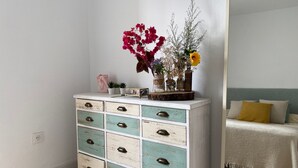 Een witte ladekast met blauwgroene laden en messing handgrepen, afgetopt met een kleine plantenopstelling.