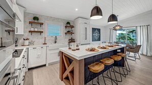 Eine moderne Küche mit weißen Schränken, Holzelementen und einer großen Kochinsel mit Barhocker.