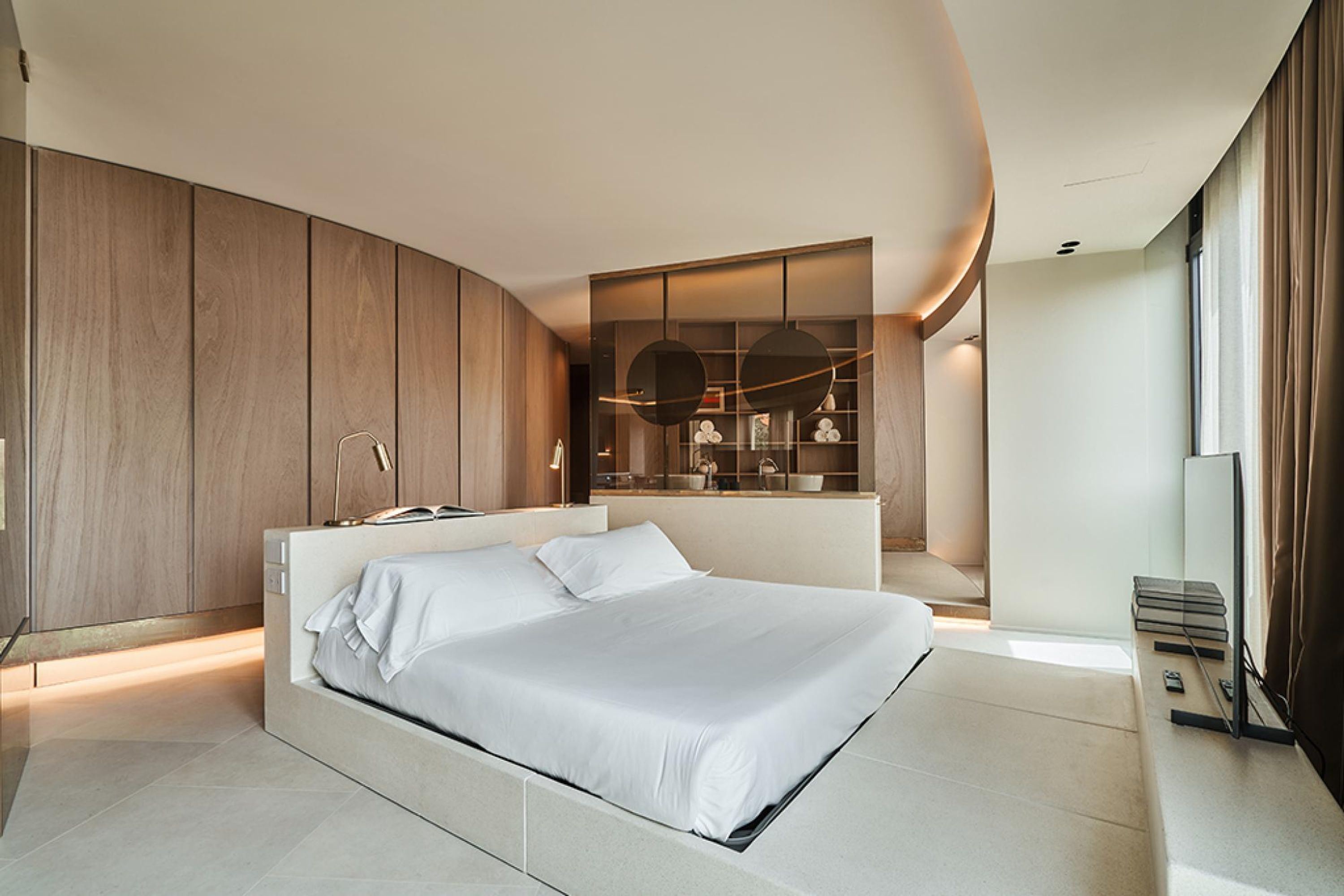 Une chambre moderne avec un grand lit, des étagères intégrées et un téléviseur.