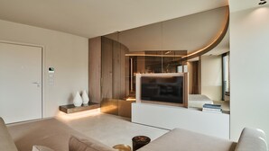 Ein modernes Wohnzimmer mit einem großen Flachbildfernseher, einer Couch und einem Couchtisch.