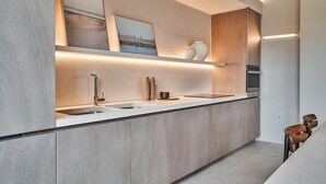 Eine moderne Küche mit einer langen Arbeitsplatte, zwei Spülen, Holzschränken und Beleuchtung unter den Schränken.