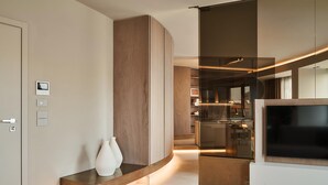 Ein modernes Interieur mit einem gebogenen Holzbodenregal, einer weißen Vase und einem Flachbildfernseher.