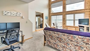 Een modern cabin interieur met een groot raam, een bureau met een computer, een bank en een televisie.