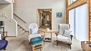 Een gezellige woonkamer met een trap, twee fauteuils, een kleine tafel en een houten vloer.