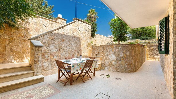 A stone-walled outdoor patio with a dining table set for four, surrounded by chairs. - 3119 A Casa di Giulia e Sofia by Barbarhouse (Racale)