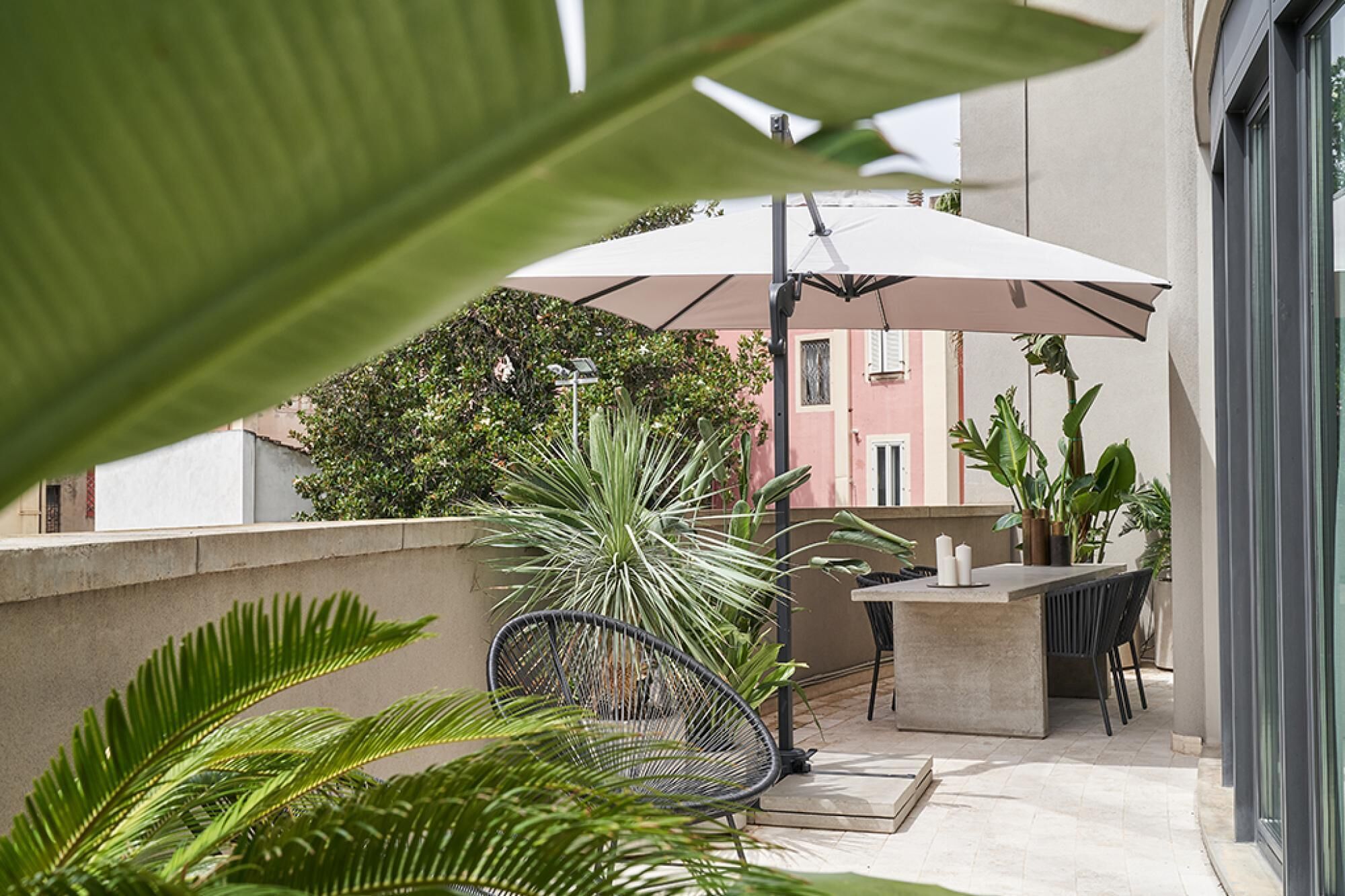 A balcony with a dining area, including a chair, table, and umbrella.