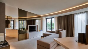 Una sala de estar moderna con un televisor de pantalla plana, un sofá, una mesa de centro y un comedor con mesa y sillas.