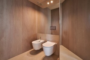 A modern bathroom with a bidet and toilet, wooden walls, and a mirror. - Residenza III Luxury Apartment (Cattolica)