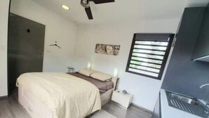 Et lille hotelværelse med seng, sengebord og et skrivebord med stol.