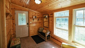 Ein Interieur einer Holzhütte mit Tür, Bank, Spiegel und Fenster.