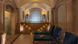 Ein Wellnessbereich mit einer Steinsitzbank, einem kleinen Pool und einer gefliesten Wand.