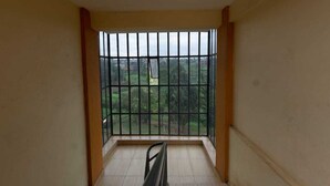 Un balcon doté d’une rambarde en métal, d’un banc et offrant une vue sur un paysage verdoyant.