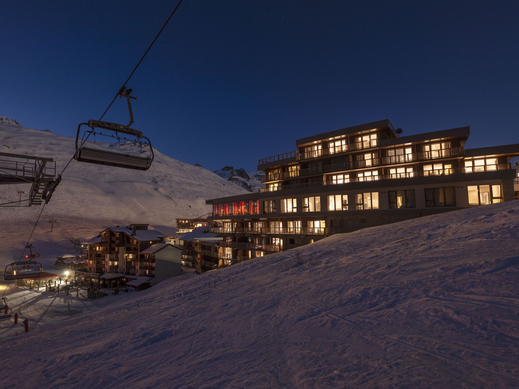 A multi-story hotel with a ski lift in the background.