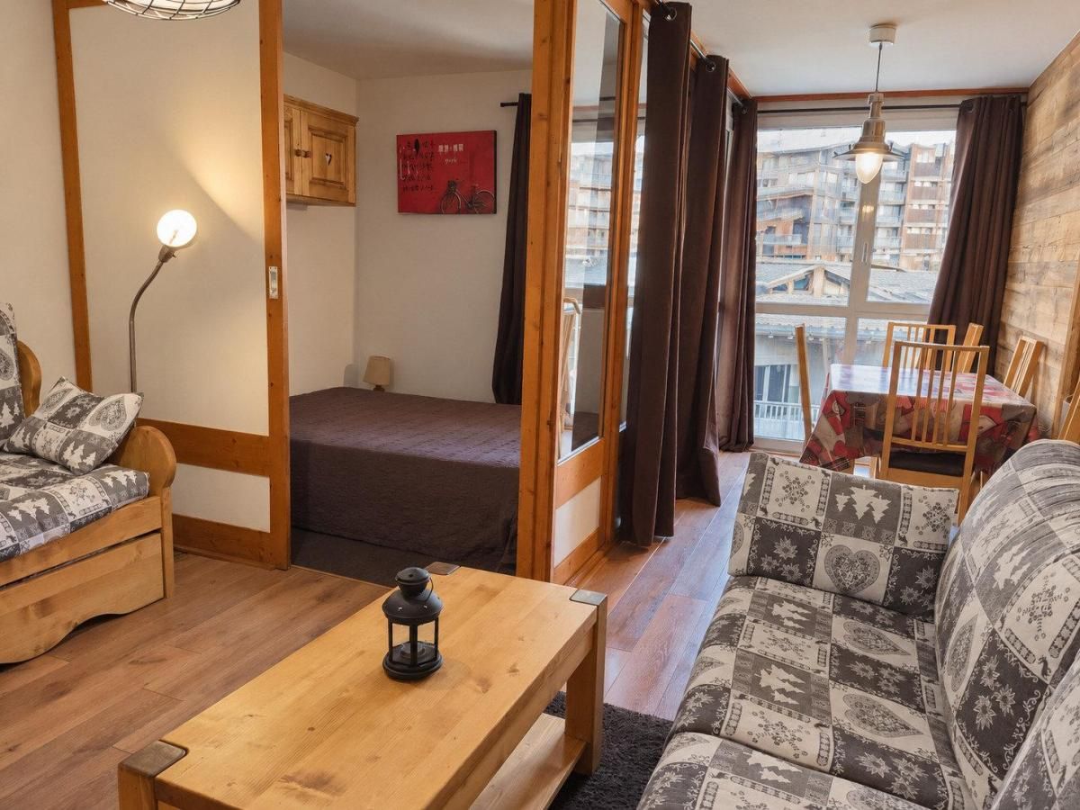Un salon chaleureux avec un canapé, une table basse en bois et une vue sur un balcon agrémenté d’une table et de chaises.