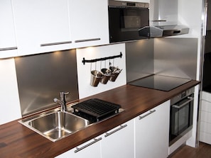 A modern kitchen with stainless steel appliances, a double sink, and a wooden countertop.