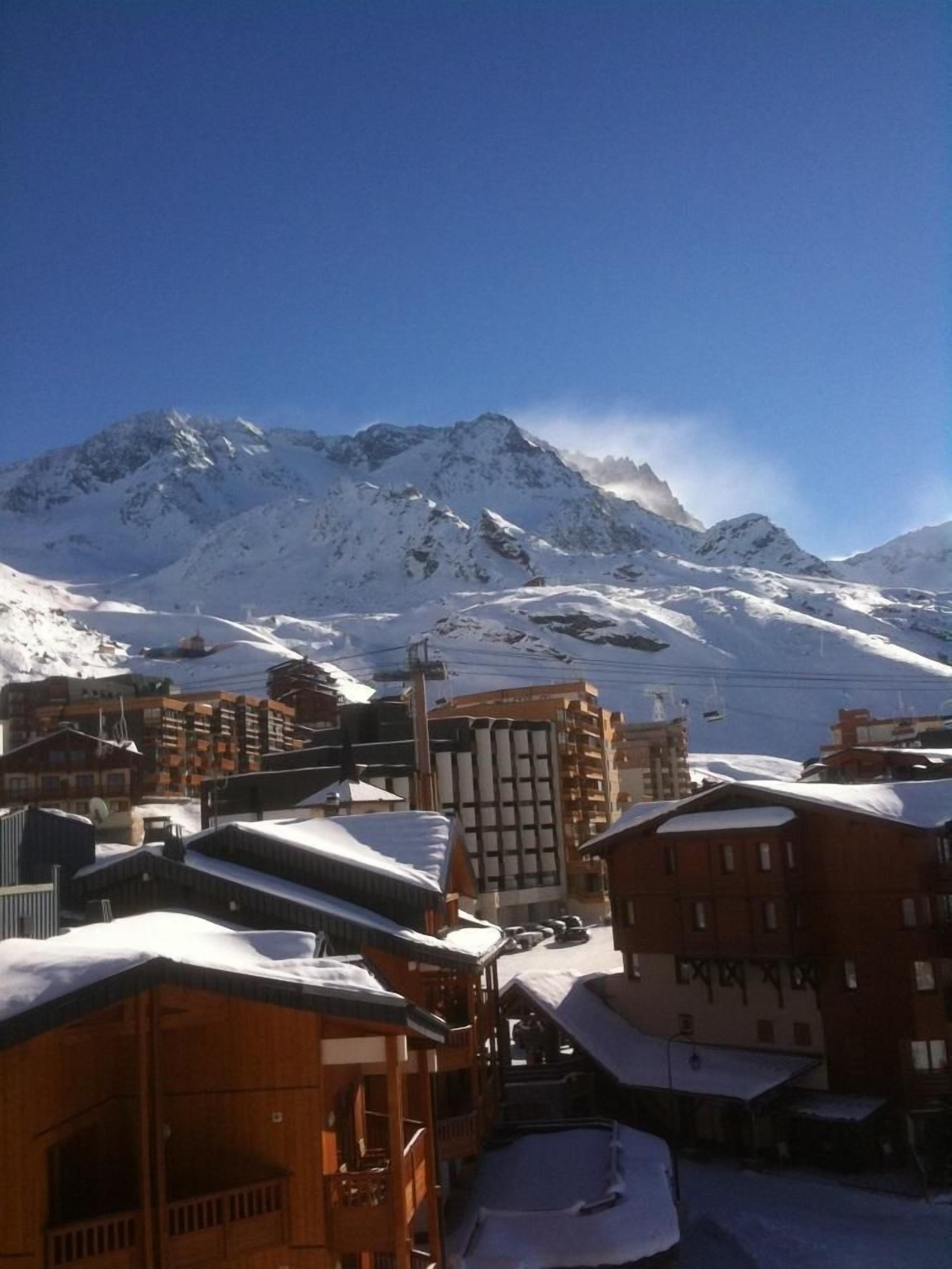A snowy mountain town with buildings and a ski lift.