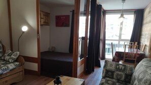 A cozy living room with a wooden coffee table, patterned sofa, and a view of a balcony.