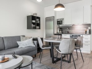 A modern kitchen with a dining area, a sofa, and a coffee table.